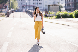 Woman wearing yellow trousers, walking along the road in the summer heat