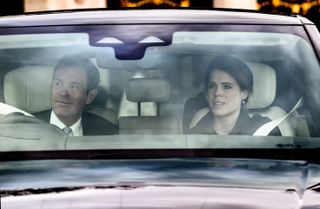 Princess Eugenie and Jack Brooksbank wearing dark coats and driving in a car