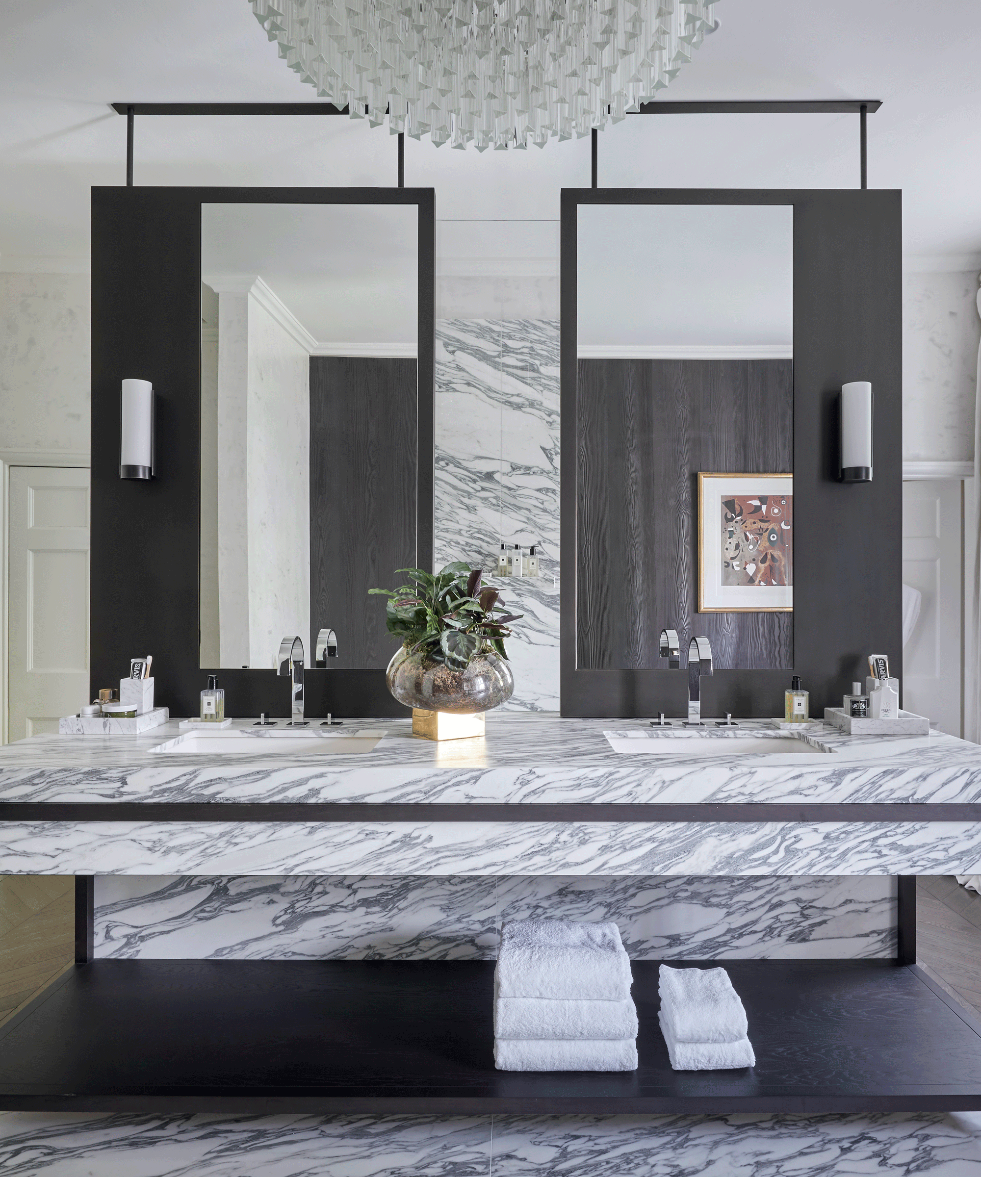A marble bathroom double vanity unit with large matching wall mirrors and towel storage below