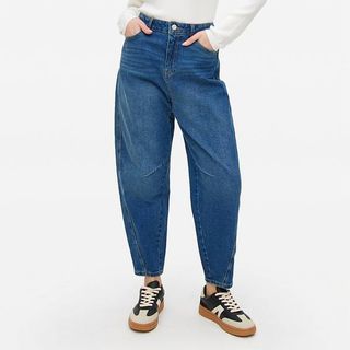 Cut off model image of a model wearing a pair of barrel leg jeans