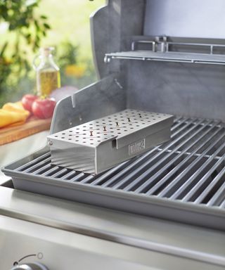 A smoker box sitting on top of a gas grill grate