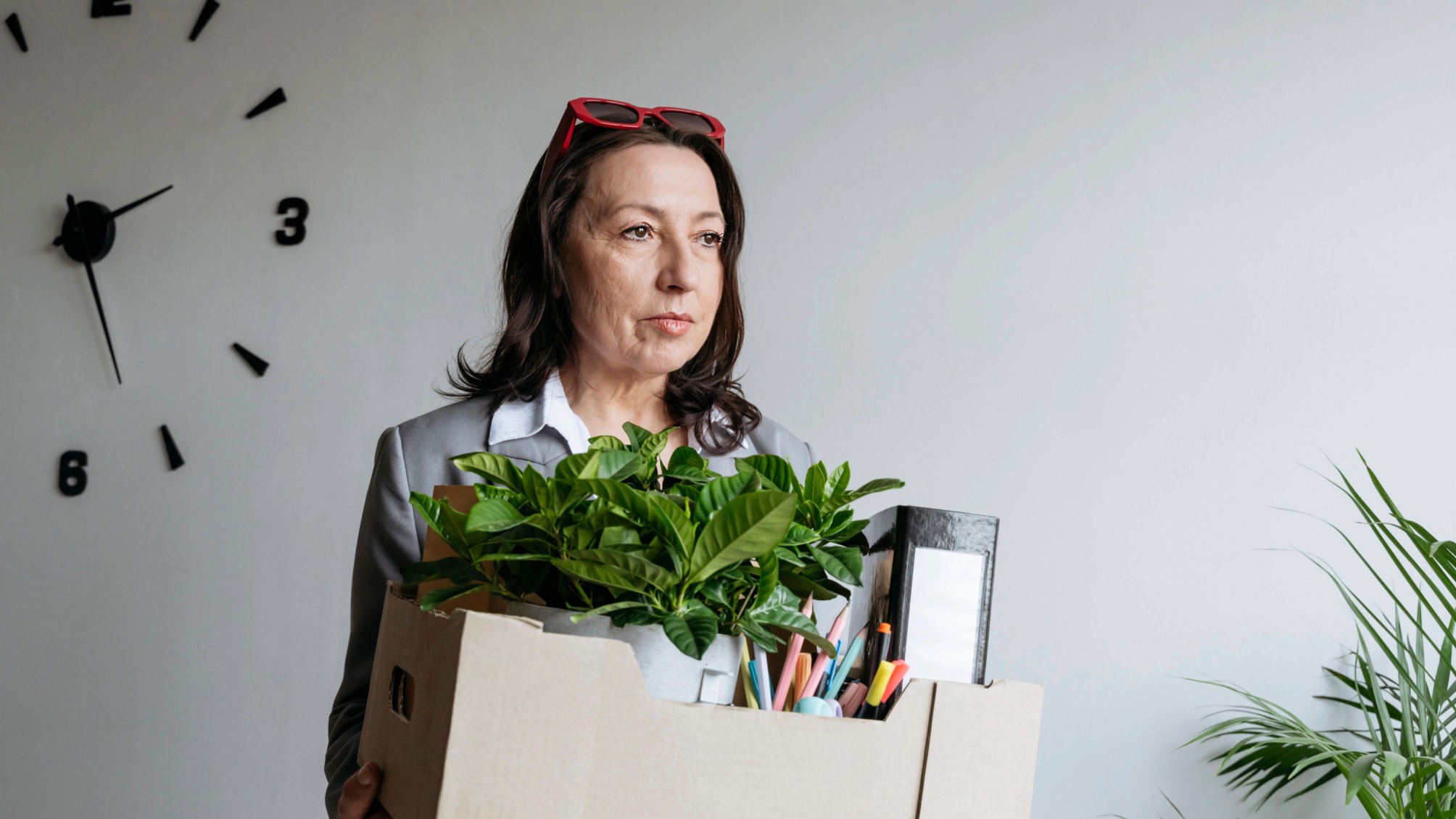 Mature businesswoman holding box with office belongings after being laid off 