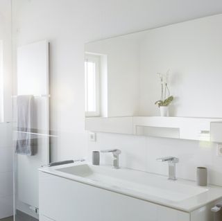 an all-white bathroom showing a vanity and nearby shower
