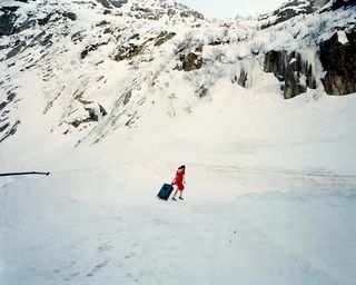 Dror For Tumi Switzerland - woman in red dress pulling luggage across Swiss Alps