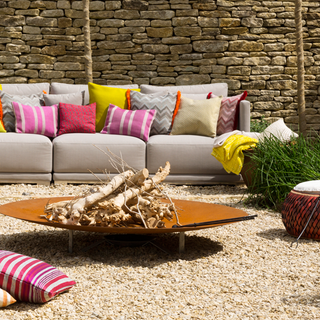 stone wall grey sofa with designed cushion outdoor wide and shallow fire bowl and woods
