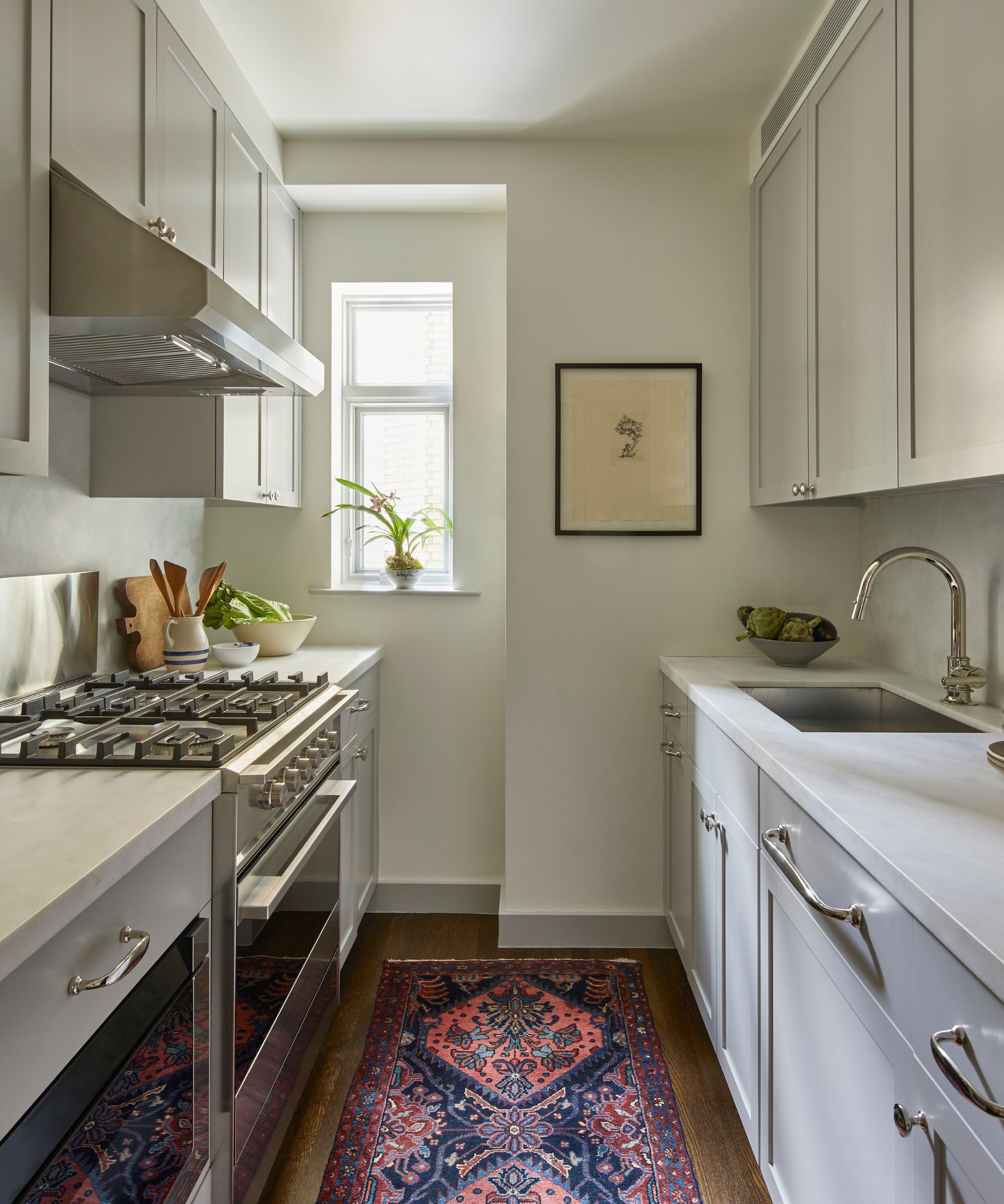 Galley kitchen with cream cabinetry, french stove and Persian rug on floor