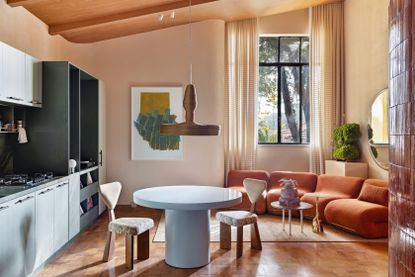 Open plan living area with terracotta modular sofa and pale blue kitchen