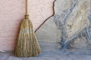 A broom leaning on a wall.