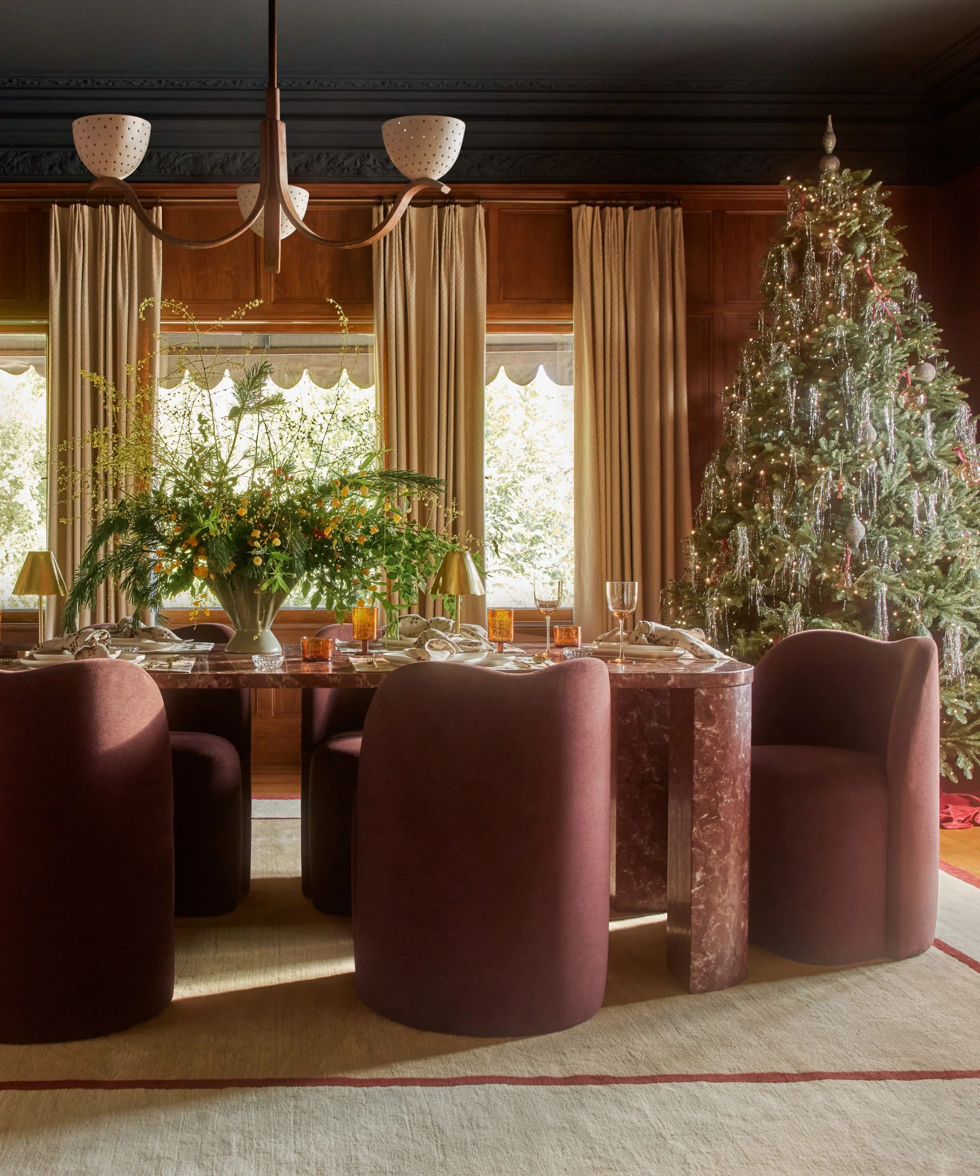 A dining room decorated for the holidays with a large Christmas tree and a seasonal centerpiece