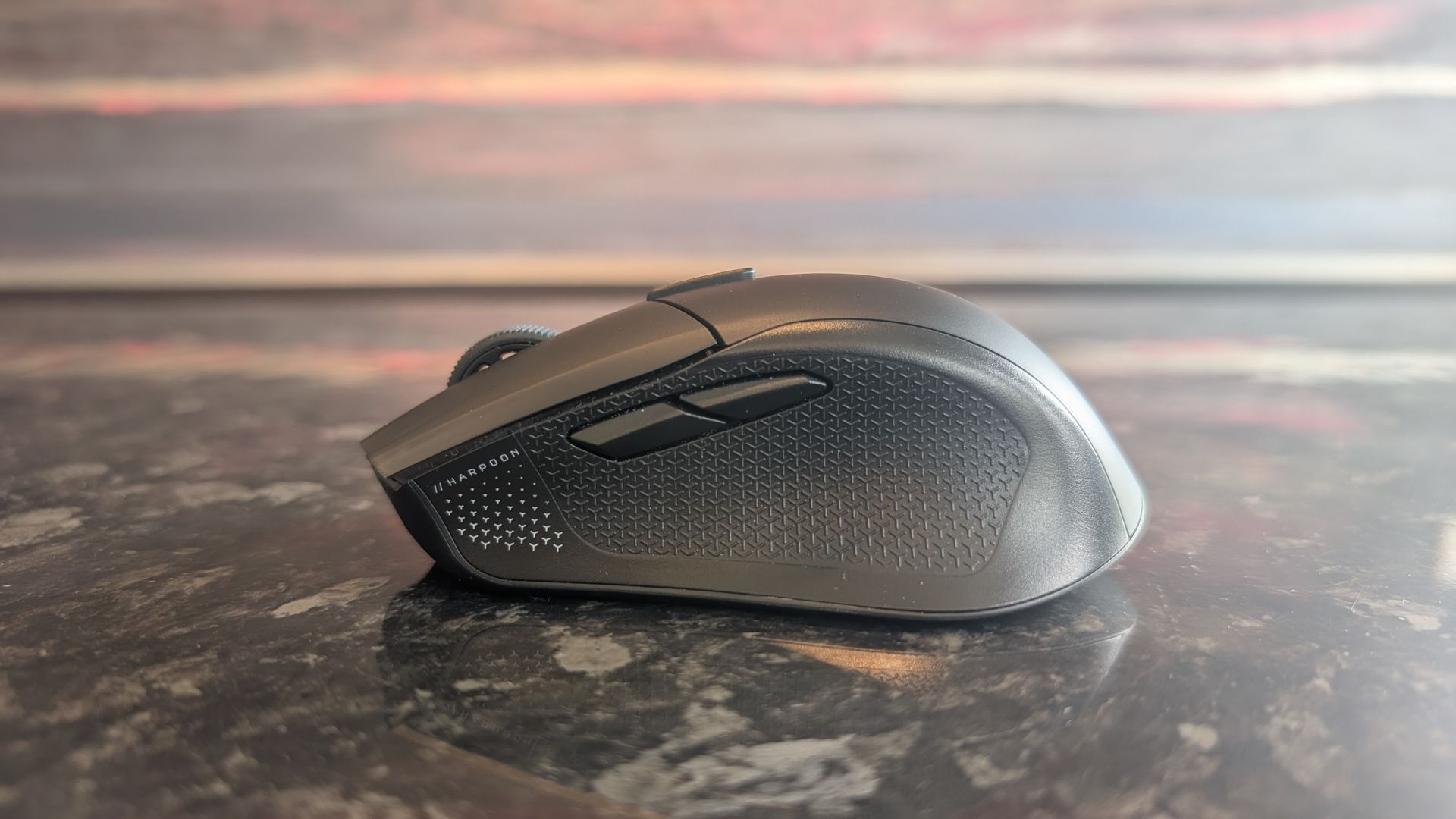 The Corsair Harpoon V2 Wireless gaming mouse pictured on a dark marble worktop.