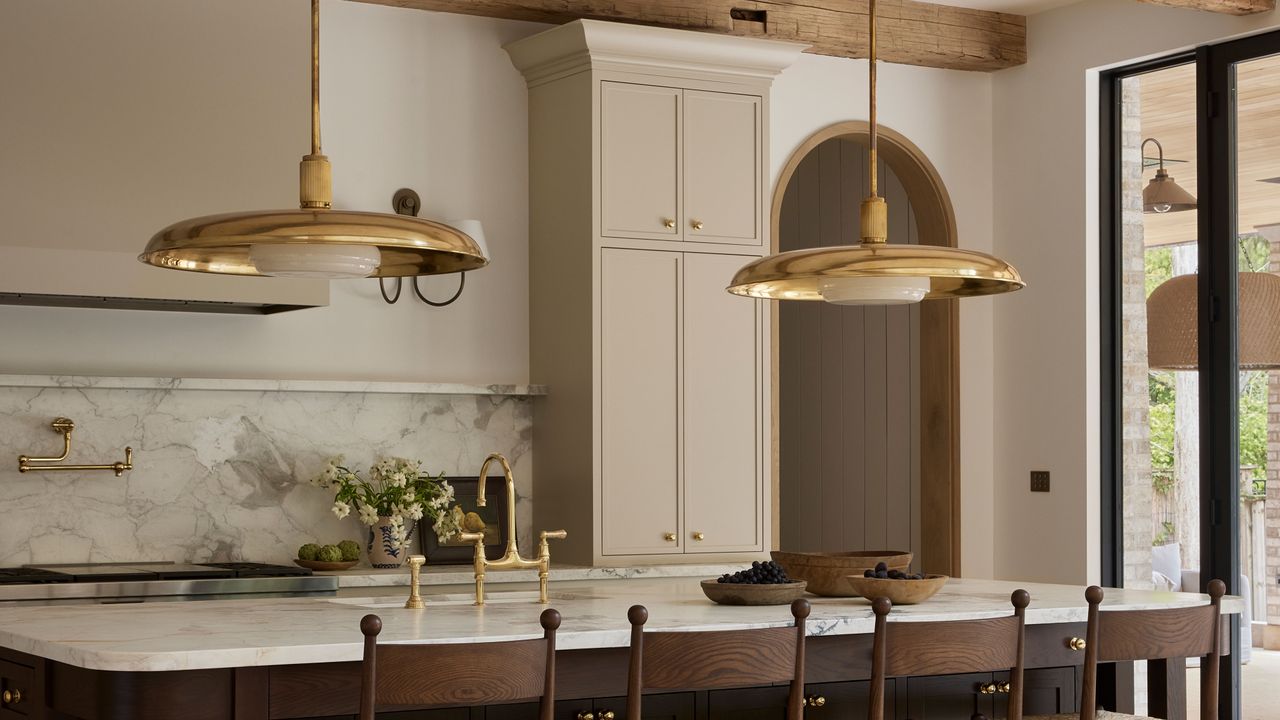 a modern beige kitchen with brass lighting