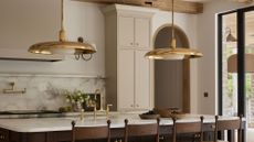 a modern beige kitchen with brass lighting