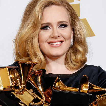 Smiling Adele holding a few Grammy awards