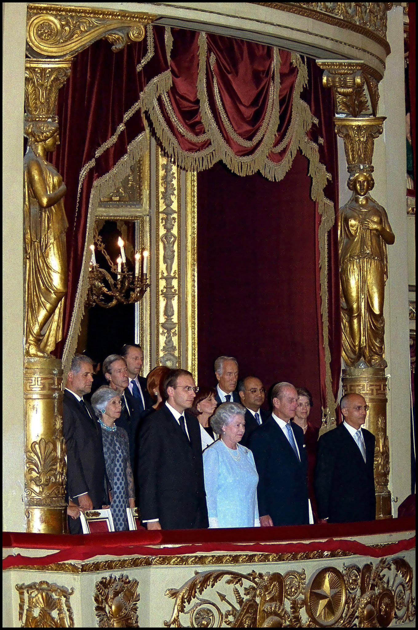 Queen Elizabeth standing in the royal box with a group of people at the La Scala theater in Milan