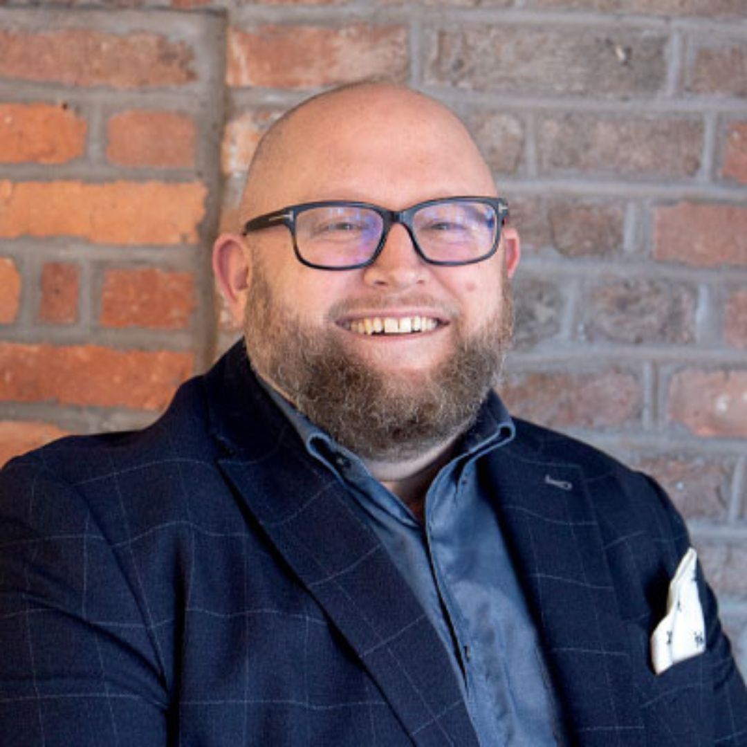 Headshot of a man against an exposed brick wall