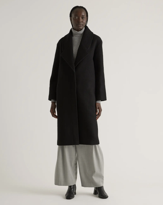 a model wears a black jacket with wide leg pants