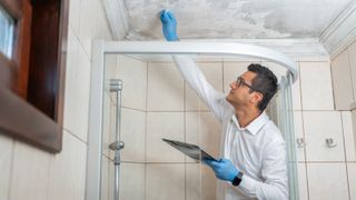 male inspecting damp ceiling in bathroom