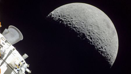 a half-lit moon seen behind the cone-shaped nozzle of a spacecraft engine