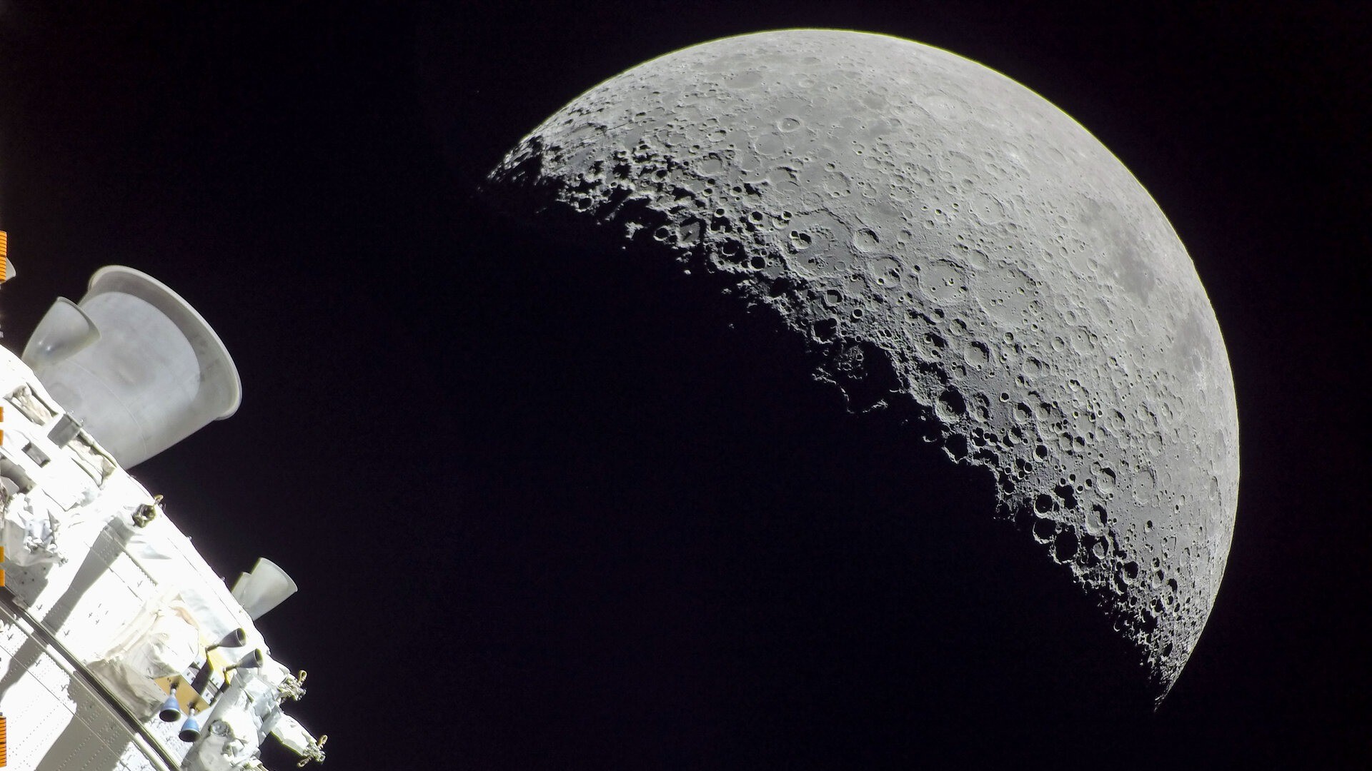 a half-lit moon seen behind the cone-shaped nozzle of a spacecraft engine