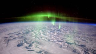 A photo of a green aurora over a cloudy Earth