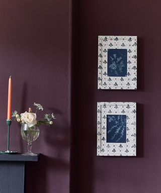 A deep purple paint in a living room with two picture frames hanging beside a black mantle