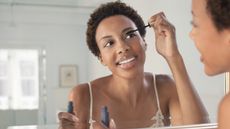 Woman applying mascara in a mirror