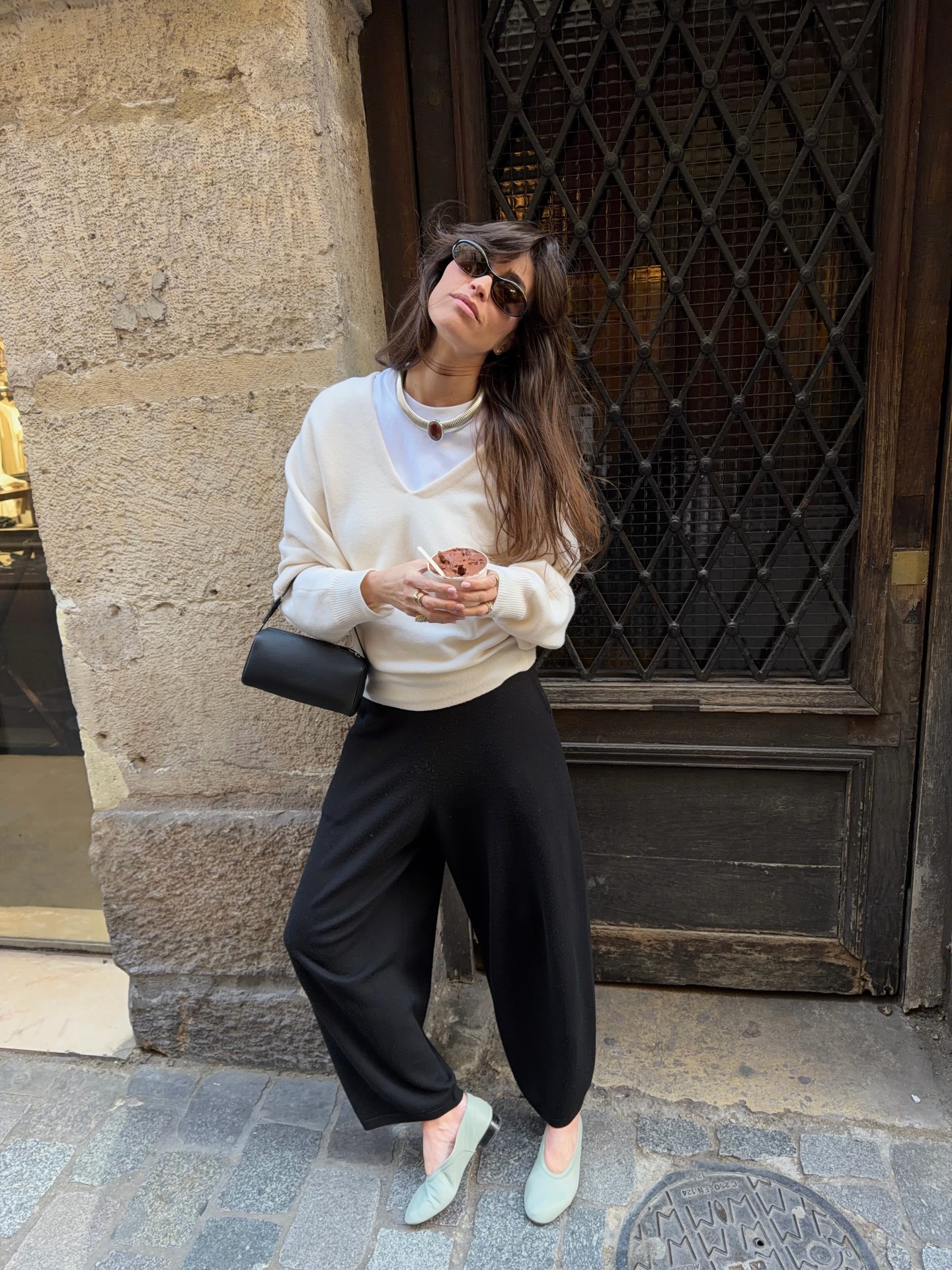 An image of @alisontoby wearing a V-neck sweater with heeled ballet pumps and black trousers.