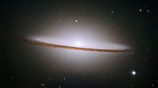 A wide, flat disc of gases with a bright white center point stretches across vast space.