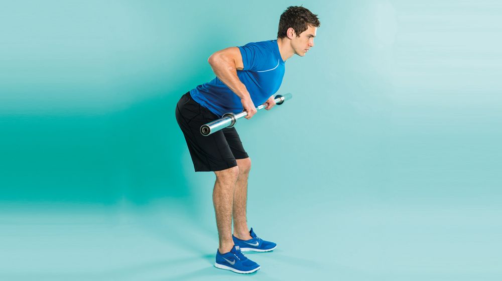 Man demonstrates the midway position of the bent-over row exercise using an empty Olympic barbell
