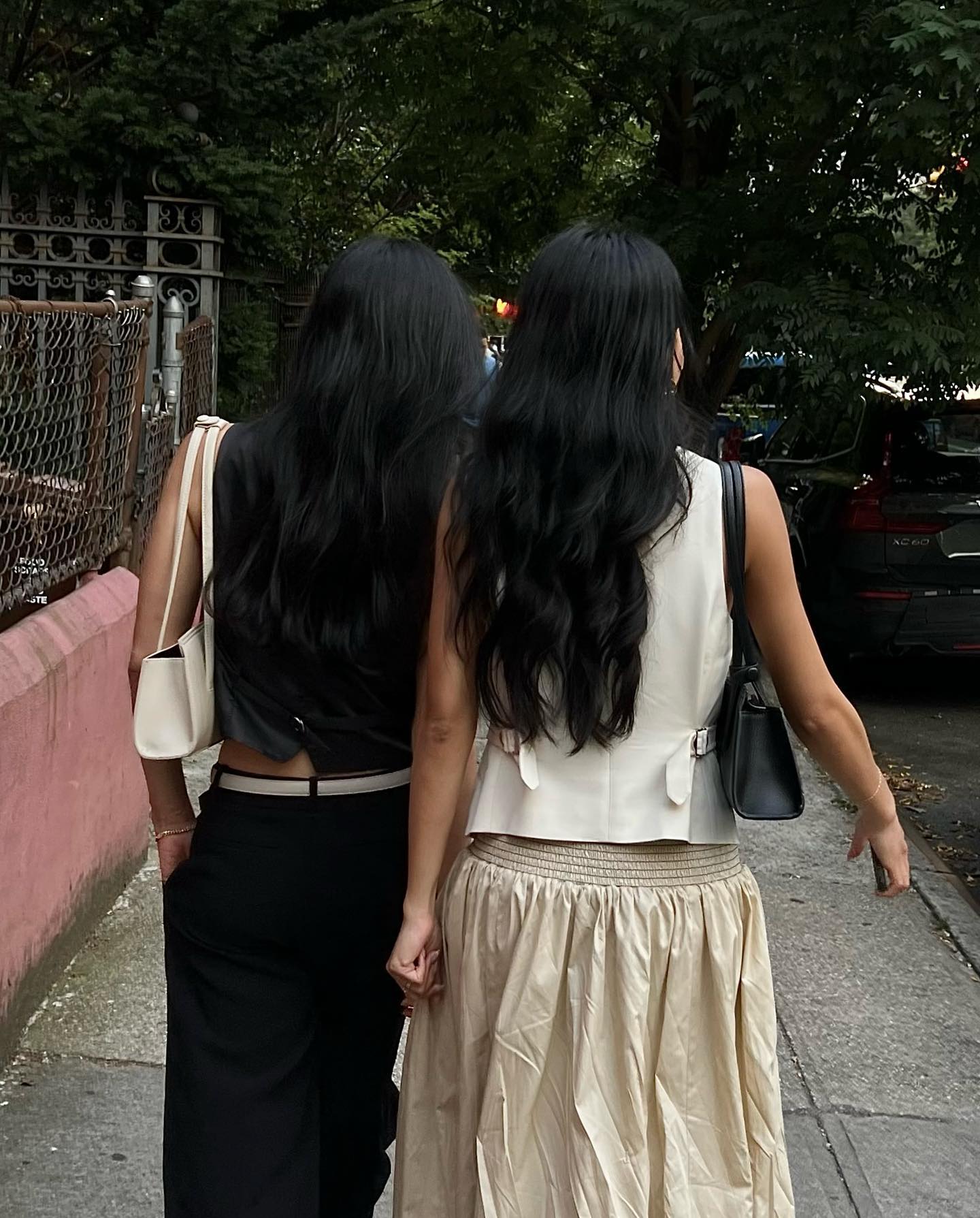 Two girls with long black hair and back toward camera wearing Freja bags under their arms.