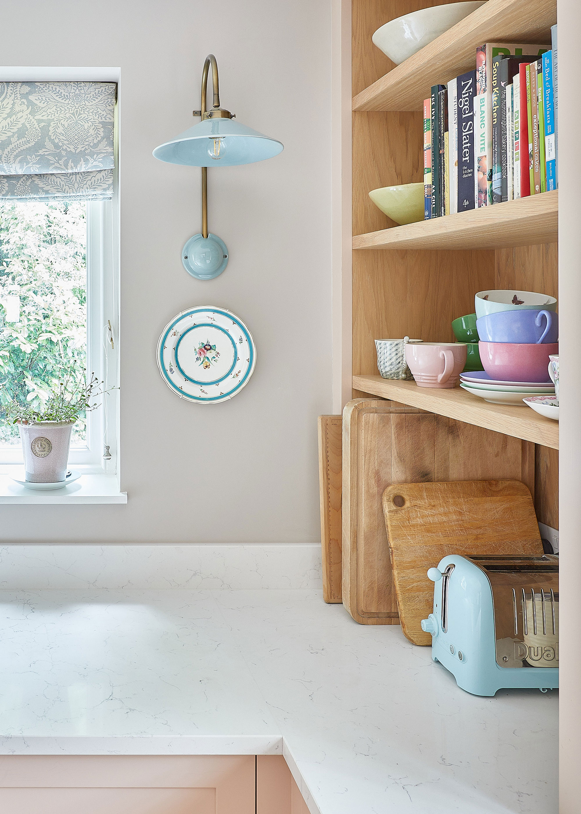pastel kitchen with kitchen shelving. On the shelf are mugs as well as books