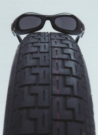 Black dior sunglasses resting on black tire