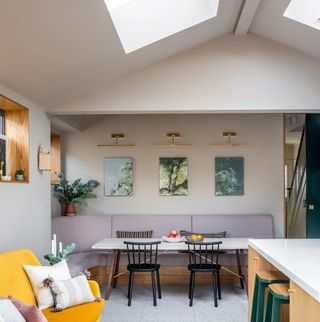 A dining table with bench seating in a white kitchen with skylights