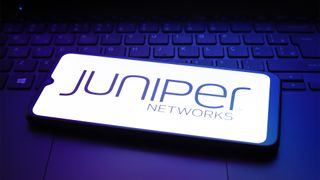 Juniper Networks logo and branding pictured on a smartphone screen placed on top of a PC keyboard.