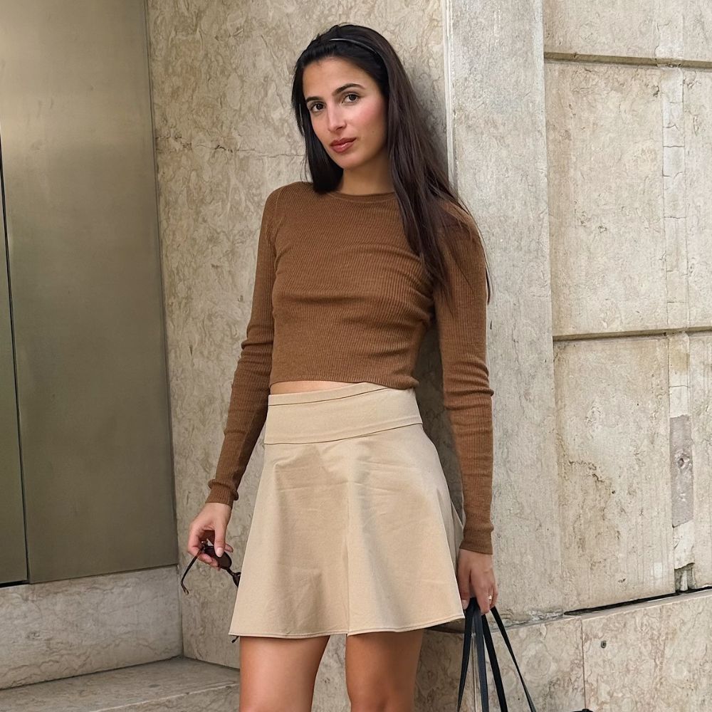 Influencer @tamaramory wears black t-bar flats with a beige skirt and brown knit.