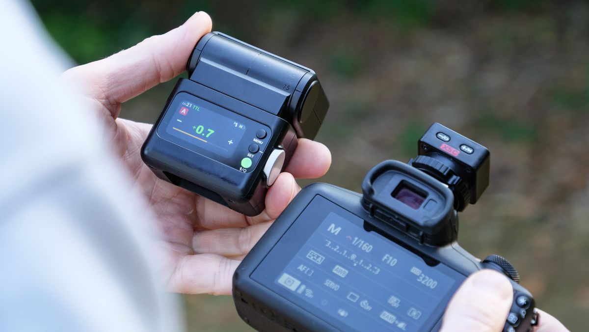 Godox iT32 camera flash alongside a Canon camera, held by photographer and TechRadar's Cameras Editor Tim Coleman,