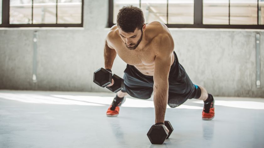 Man performing a dumbbell push up in a fitness center