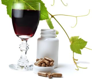 A glass of wine and pills of resveratrol.