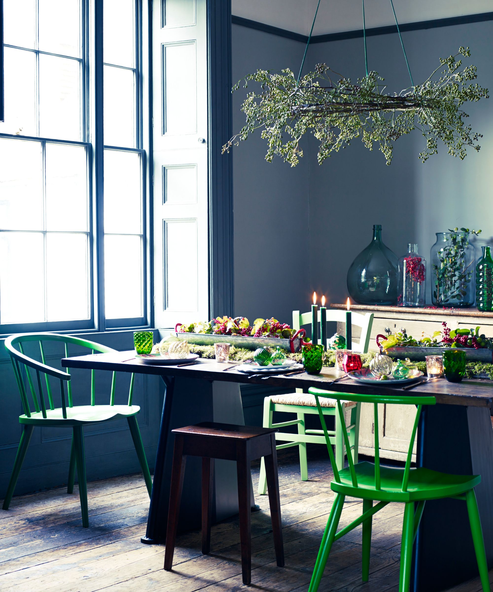Christmas table with bright green chairs and a garland hanging above
