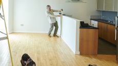 A landlord does some measuring in an empty apartment.