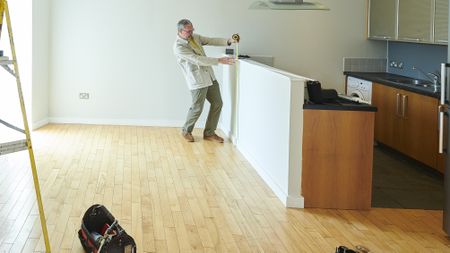 A landlord does some measuring in an empty apartment.
