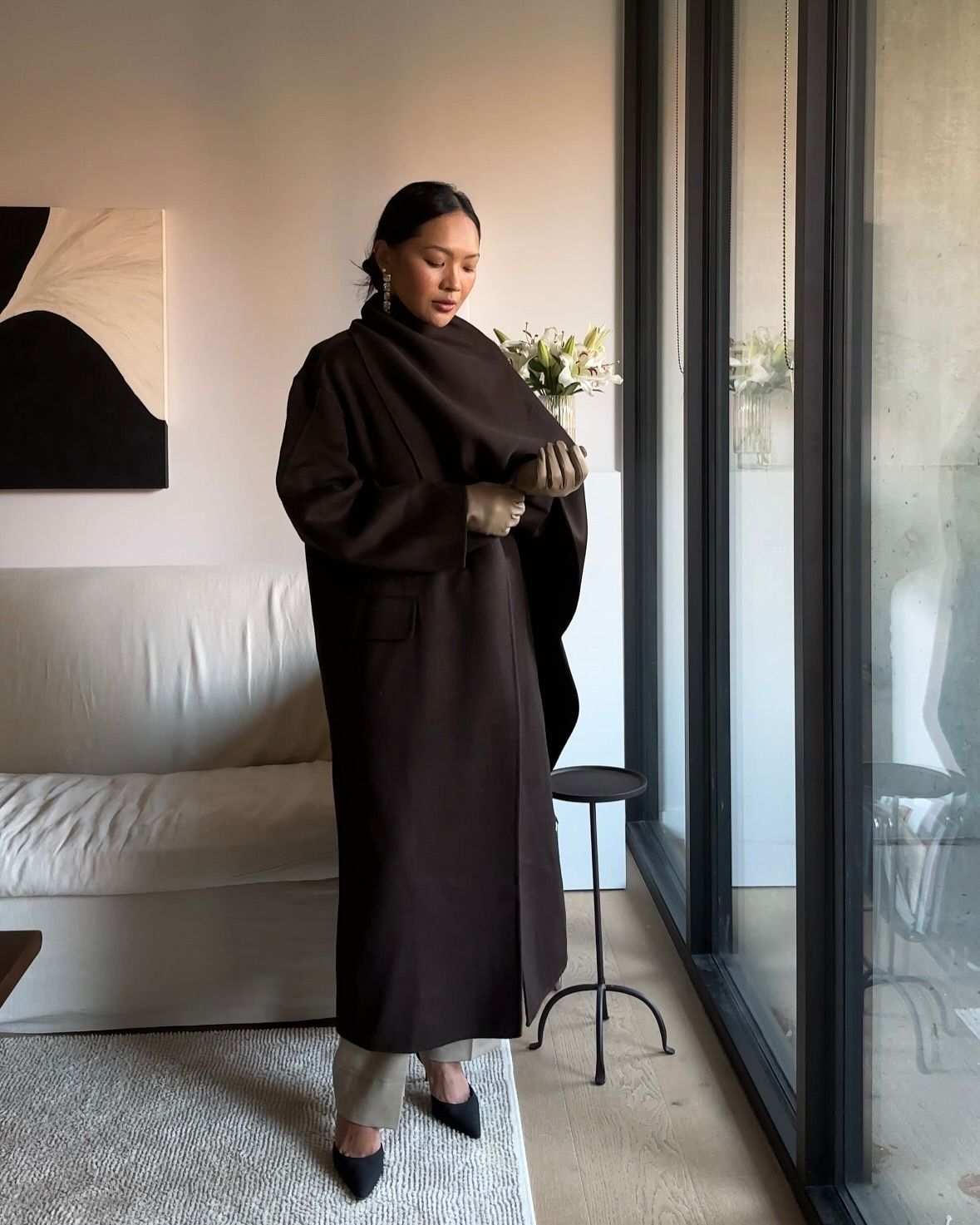 Dawn Tan wears a brown scarf coat with trousers and pointed-toe heels.