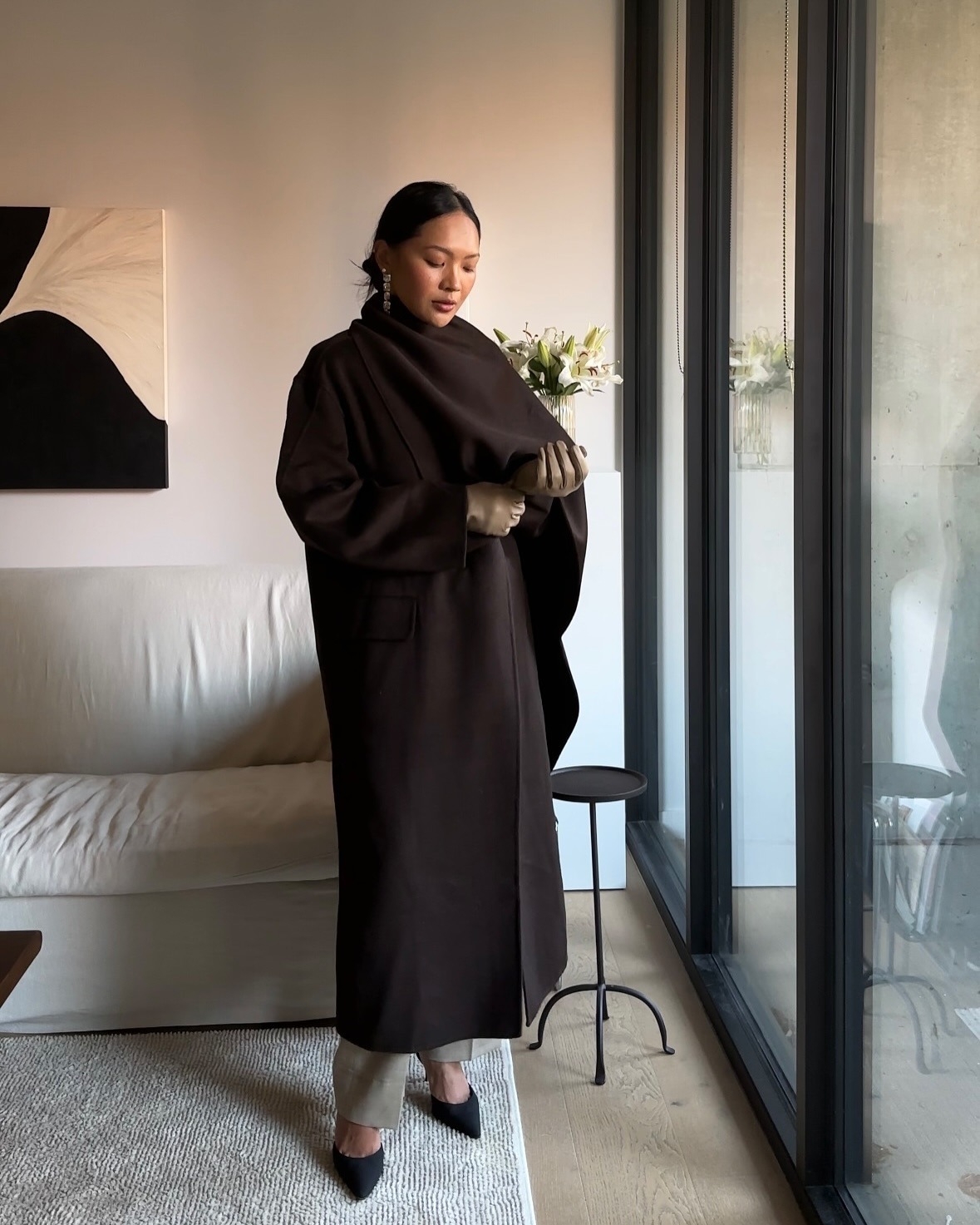 Dawn Tan wears a brown scarf coat with trousers and pointed-toe heels.