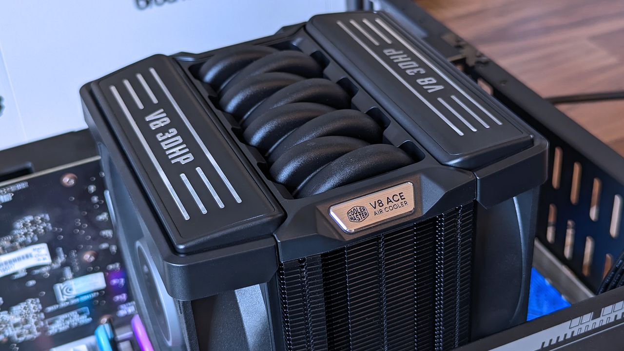 Close‑up of the Cooler Master V8 ACE 3DHP CPU cooler installed inside a test bench, showing its engine‑inspired shroud, curved heat pipes, and fin stack.