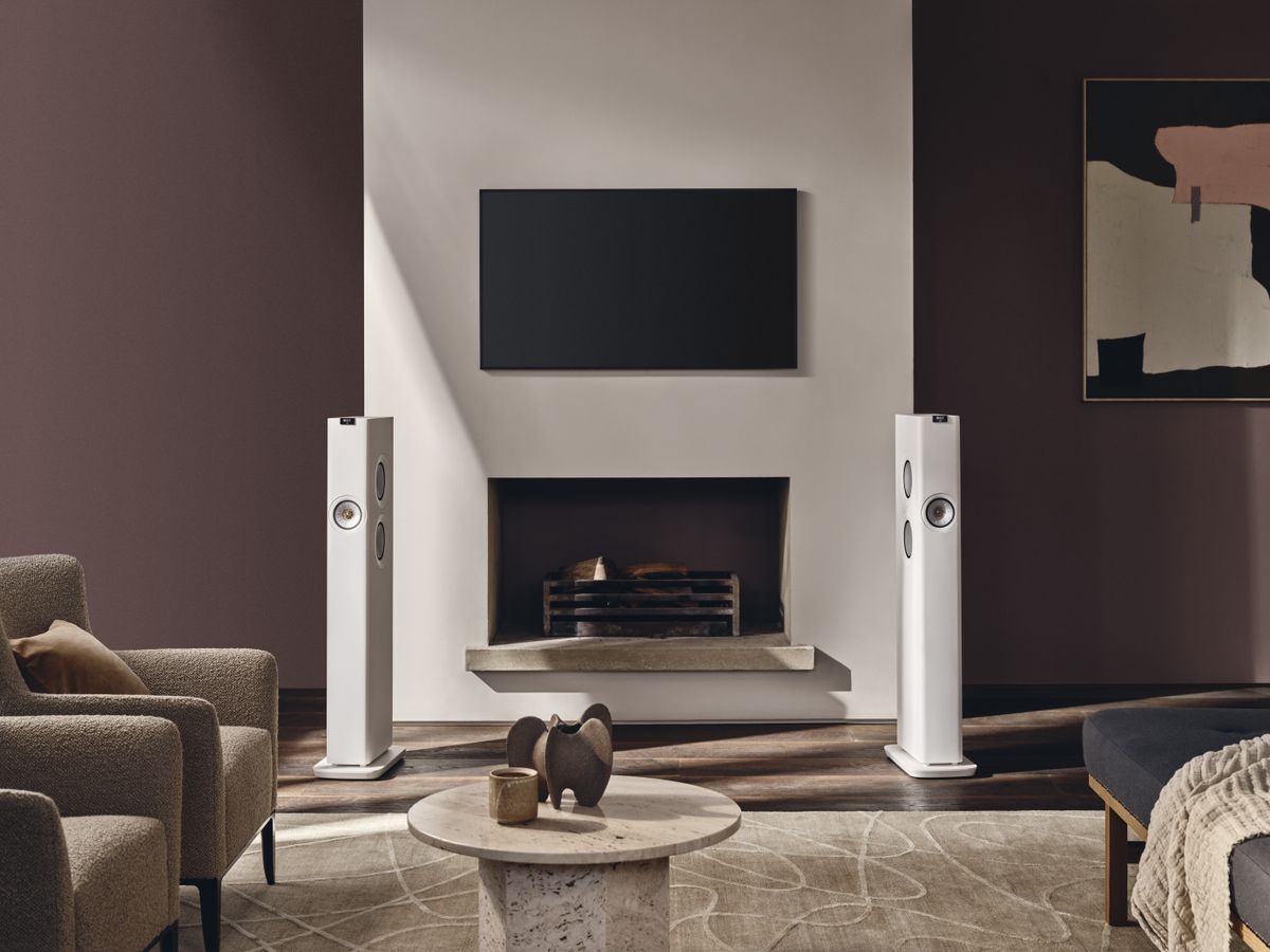 KEF LS60 wireless speakers in a living room setting next to a fireplace