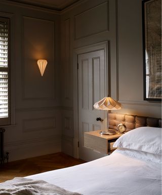 Layered bedroom lighting tips paired with a dark color scheme and white bed linens.