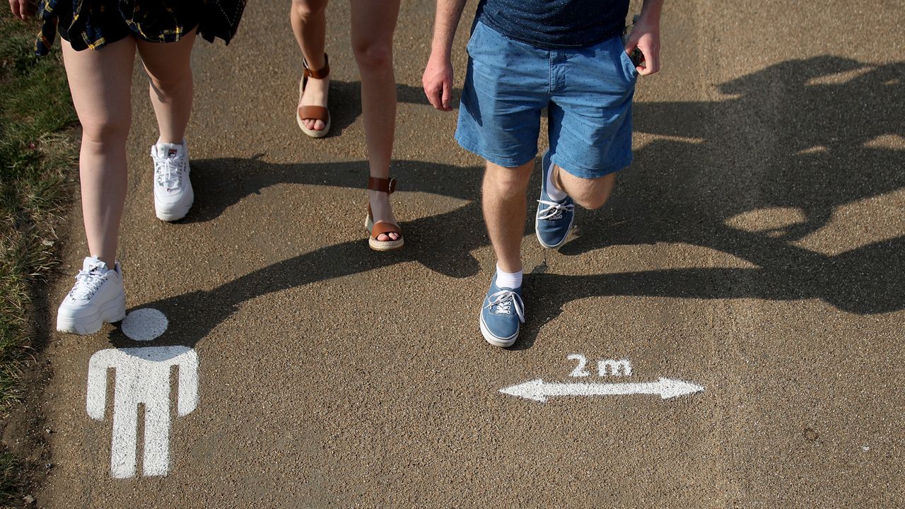 People walk past the social distancing markings on the ground at Queen Elizabeth Olympic Park.