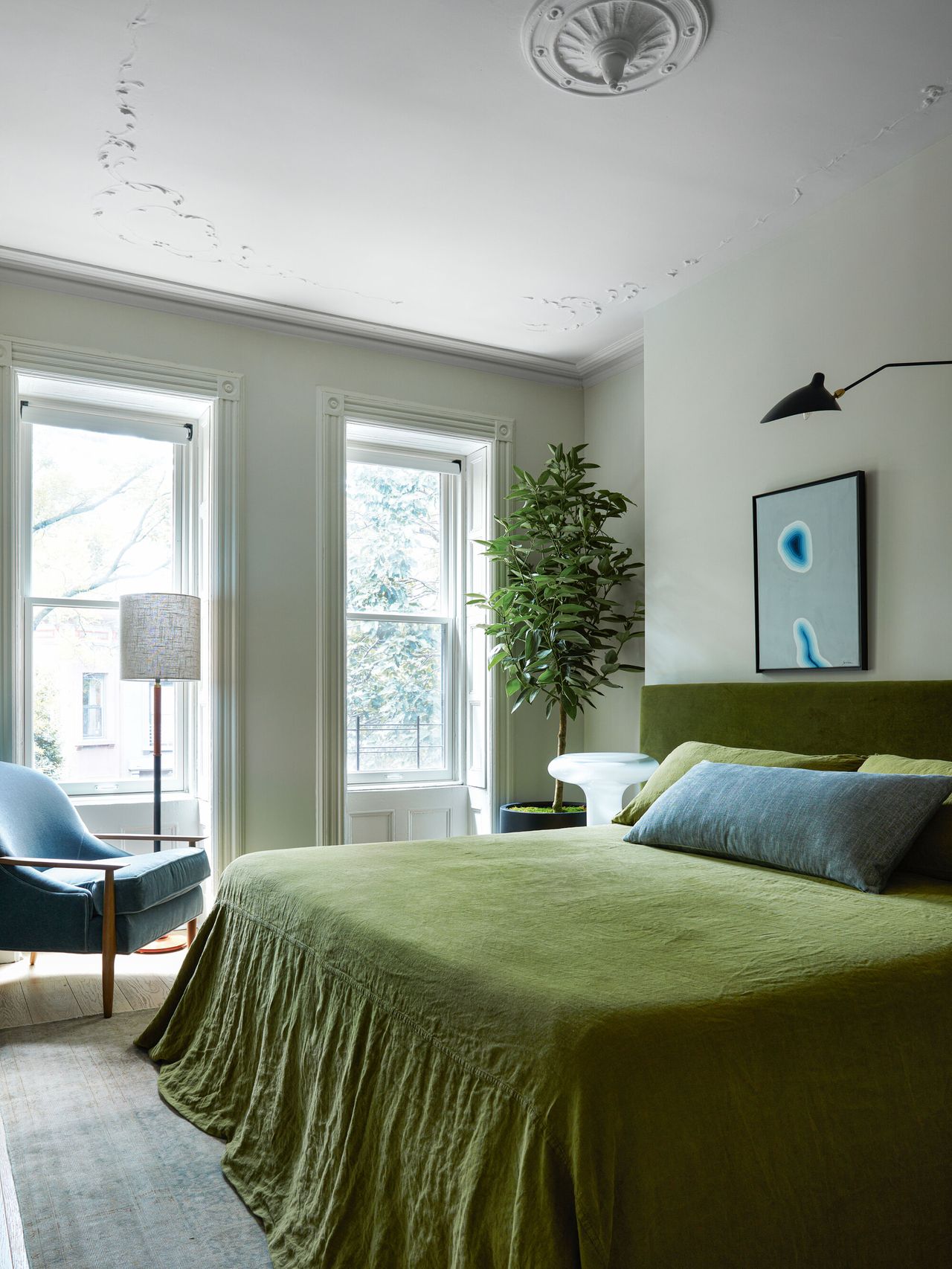 A double windowed main bedroom with a ceiling cornice detail and green bedding