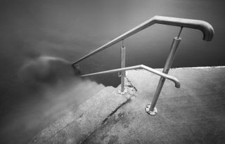 A black and white photography of some stairs leading in to water