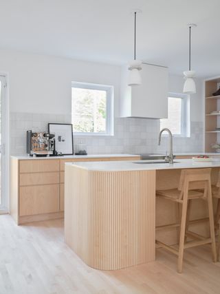 A kitchen with light wood island, and white countertop